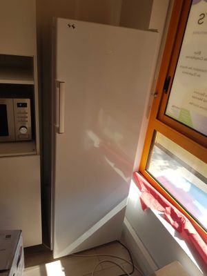 a white refrigerator in the corner of a kitchen next to a window