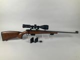 a rifle with a scope and a scope holder on a white background