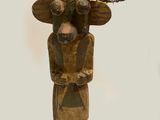 a wooden sculpture of a man with feathers on his head
