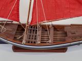 a model of a boat with red sails on a wooden stand