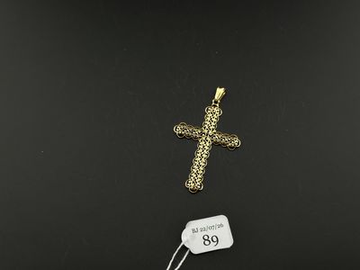 a gold cross pendant with a price tag on a black background