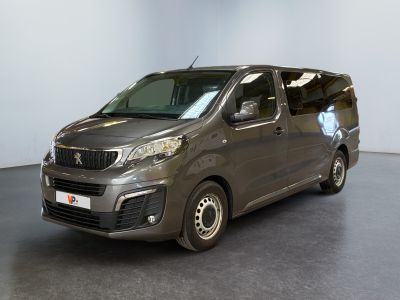 La camionnette grise est garée dans une grande pièce au sol noir.