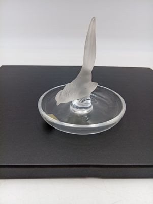 sculpture représentant un oiseau sur une plaque de verre posée sur une surface noire