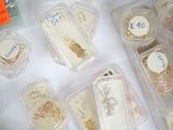 many different types of jewelry in plastic containers on a table