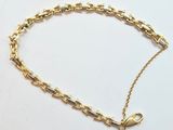 gros plan d'un bracelet en chaîne en or sur une surface blanche