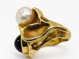 une image représentant une bague en or ornée d'une perle et d'un onyx noir