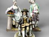 two figurines of people sitting on a table with a plate