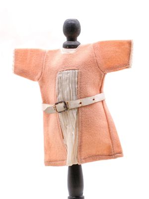 un manteau couleur pêche sur un mannequin, avec une ceinture à la taille