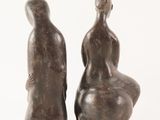 two statues of a man and a woman sitting on a rock