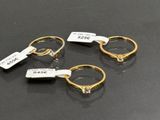 three gold rings with tags on them sitting on a table