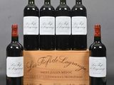 six bottles of red wine in a wooden crate with a grey background