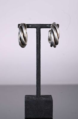 a close up of a pair of silver hoop earrings on a black stand