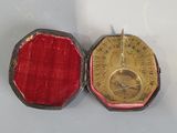 une petite boîte rouge contenant une médaille en or