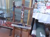 an easel with a glass case and a chair in the room