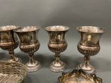 four silver vases and a basket are sitting on a table