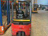 a red forklift in a large warehouse with pallets