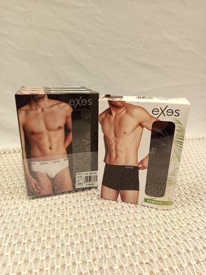 two boxes of men ' s underwear sitting on a bed next to each other