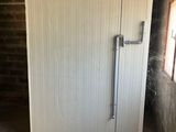 a white door in the middle of a room with a brick wall