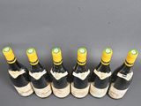 six bottles of wine lined up in a row on a table