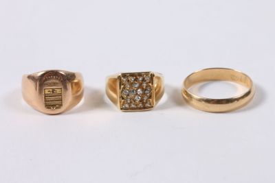 three gold rings with diamonds on them on a white surface