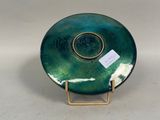 an image of a green and gold plate with a tag on it