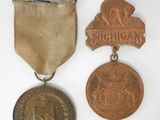 deux médailles et une médaille posée sur une surface blanche, sur fond blanc