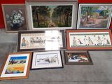 many framed pictures on the floor next to a red wall
