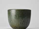 green glazed bowl on a white surface with a light gray background