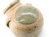 un vase marron et vert posé sur une surface blanche