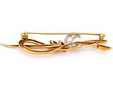 a close up of a gold brooch with leaves on it