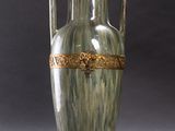 a green vase with a gold decoration on it