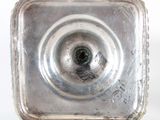 a silver plate with a hole in it on a white surface