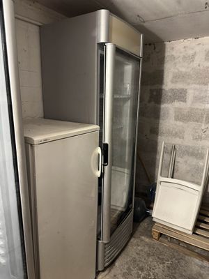 un réfrigérateur dans un coin de la pièce, à côté d'une poubelle