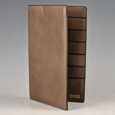 un gros plan d'un portefeuille en cuir marron posé sur une surface blanche