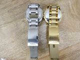 two watches sitting on a wooden table next to each other