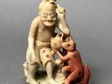 a figurine of a man sitting on a rock with a monkey