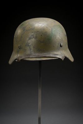 un vieux casque posé sur un support, sur fond noir