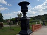 a black vase sitting on a stone bench in a park