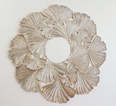 a silver wreath made of leaves on a white wall