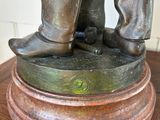 a bronze statue of a man standing on top of a wooden table