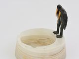 a small figurine of a monkey sitting on top of a bowl of water