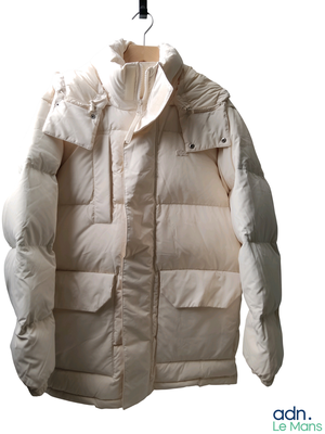 une veste blanche suspendue à un cintre sur un mur blanc