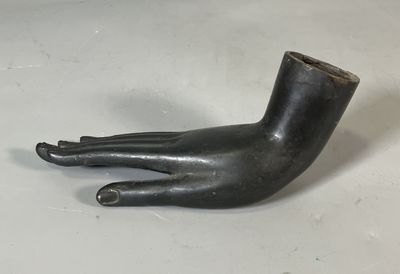 sculpture représentant une main tenant une pipe sur une surface blanche