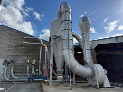 un gros tuyau métallique à côté d'un bâtiment, avec le ciel en arrière-plan