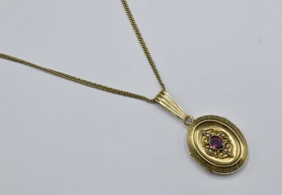 a close up of a gold necklace with a purple stone