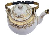 a white tea pot with a gold decoration on it