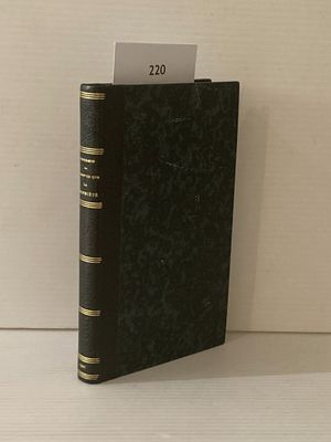un livre noir aux bords dorés posé sur une table blanche