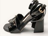 a black shoe with a gold buckle on the heel
