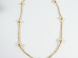 a gold chain necklace with beads on a white background