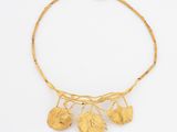 a close up of a gold necklace with leaves on it